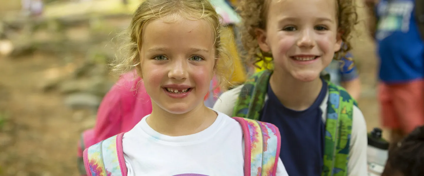 Two little campers smile for the camera as they wait to begin an activity.