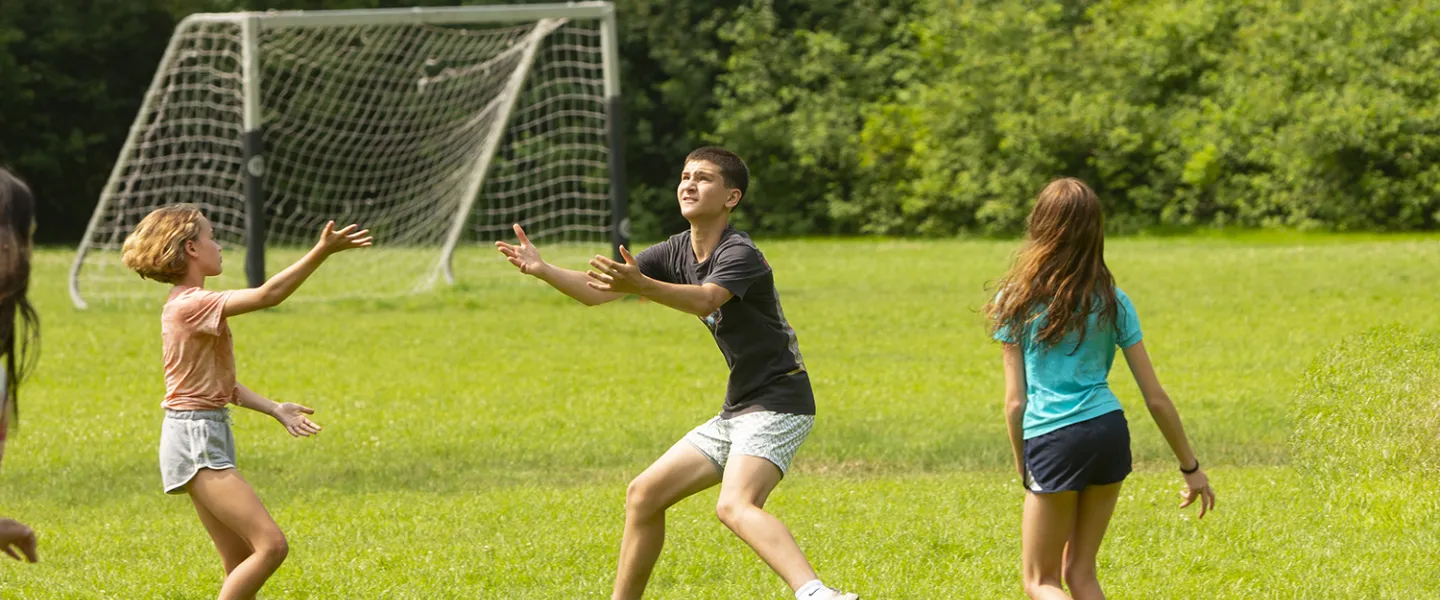 Campers hustle to try and catch the kickball going through the air.