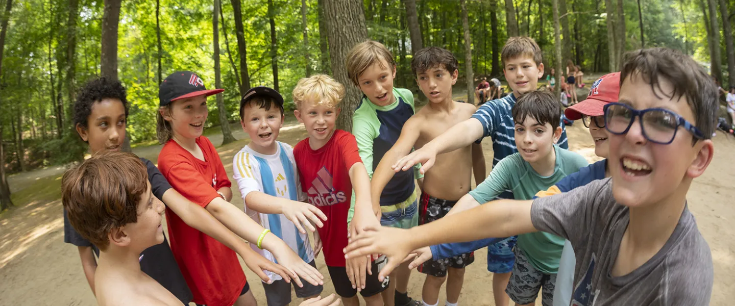 A big group of campers gathered together with their hands all in.