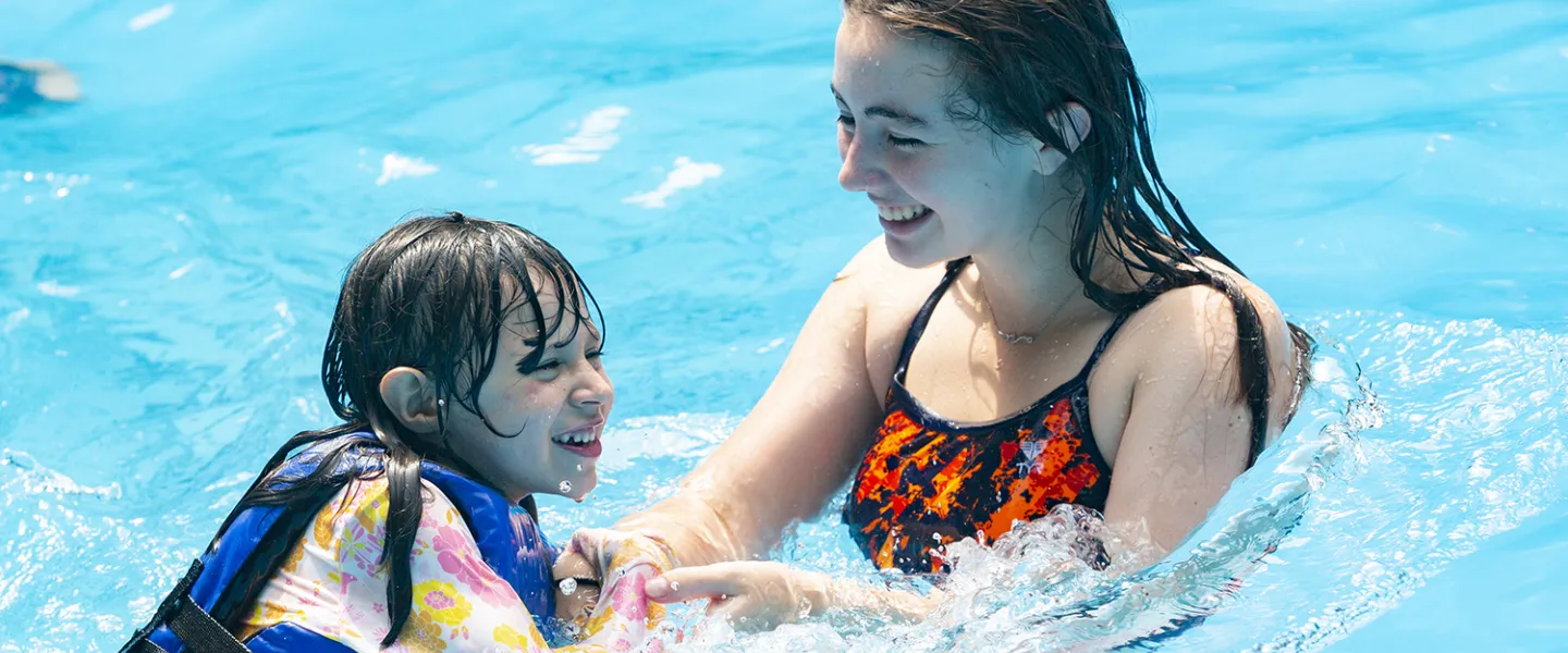 A consular in the pool with her camper helping her move through the water. 