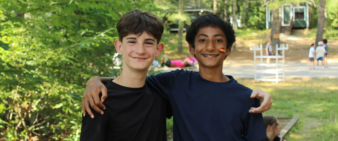 Two friends stand right next to the camps lake. 