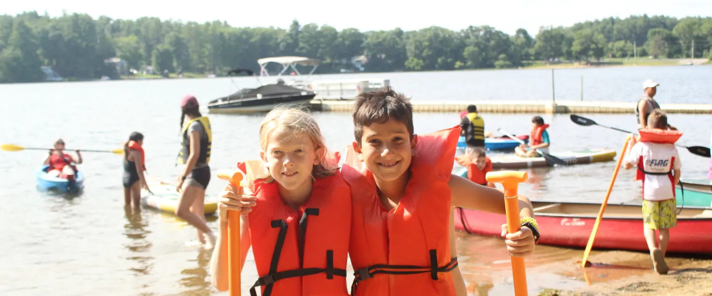 2 campers outside getting ready to go kayaking.