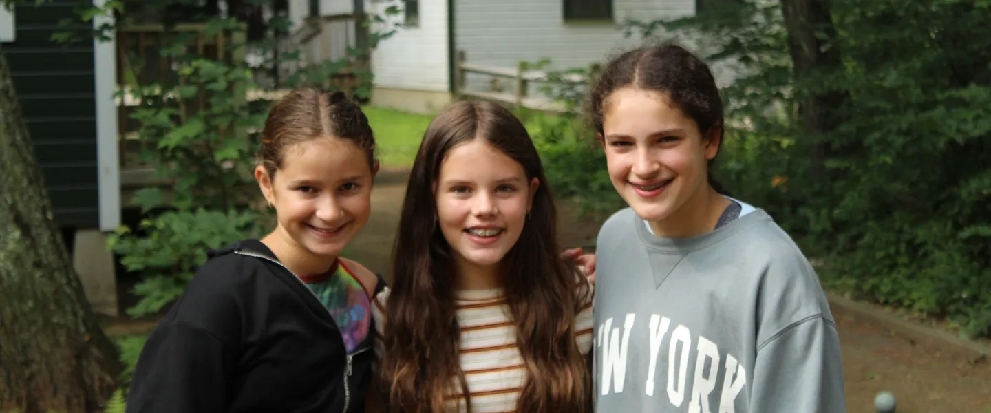 3 campers standing out front of their cabin.