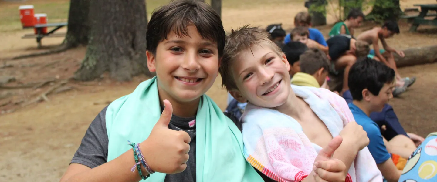 Two friends stand with their pool towels before they go swim.