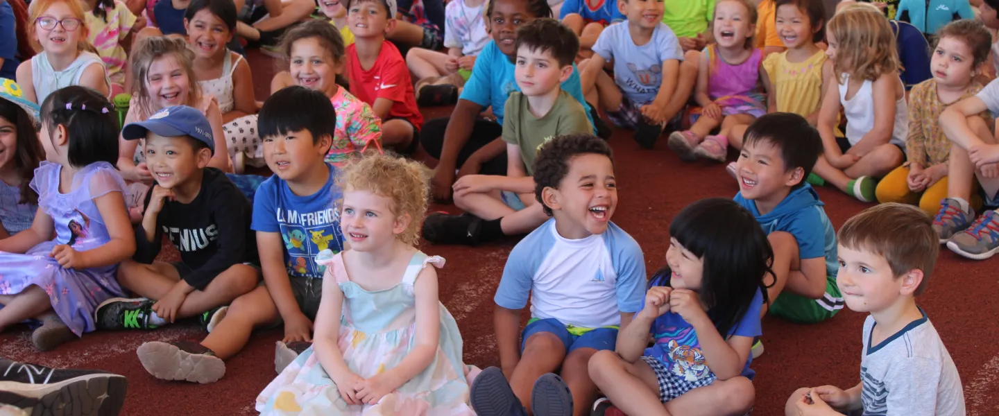 Young campers watch a magic show which has them all laughs.