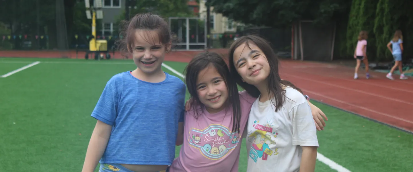 Three camp friends gathered together giving big smiles to the camera.