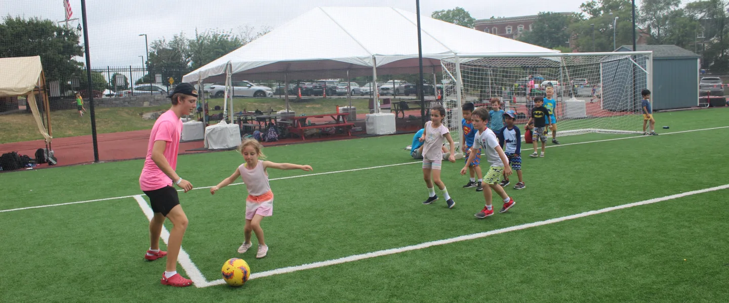 Campers working together to try and take the soccer ball from their consular.