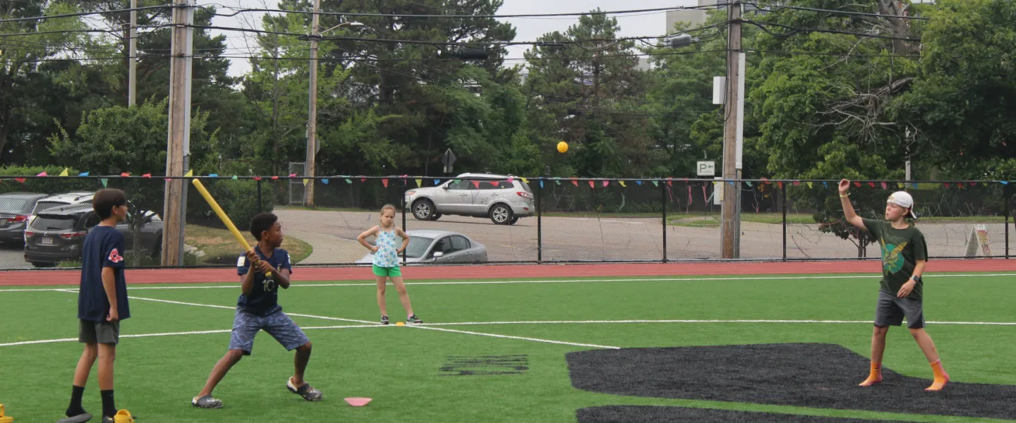 Older campers and their consular playing some wiffle ball on the field.