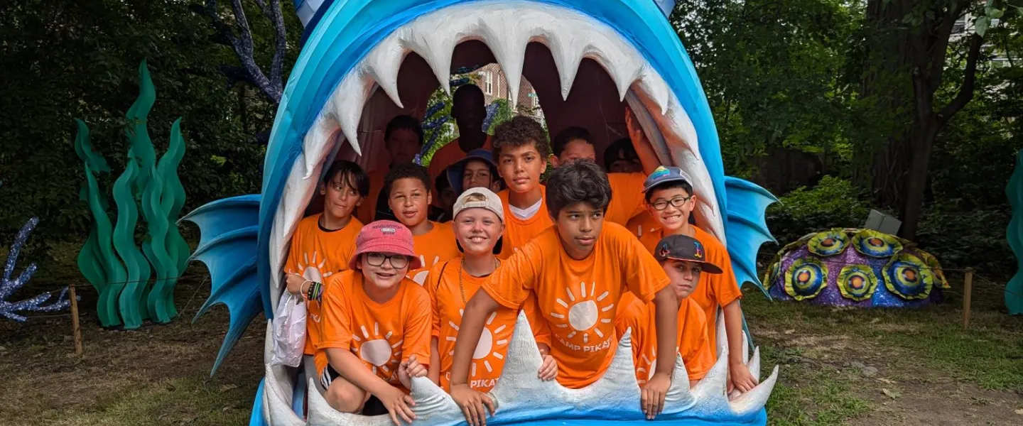 Campers on a field trip, sitting inside the mouth of a giant fake fish. 