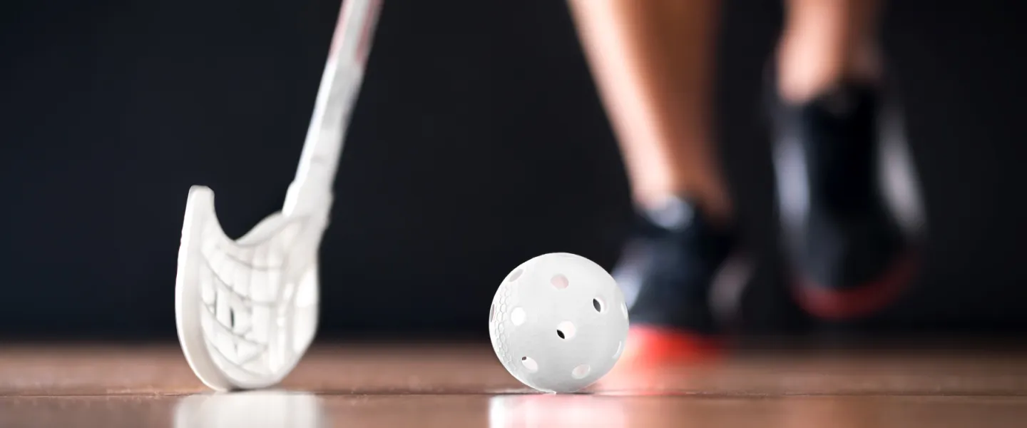 youth feet on court floor with ball and floor hockey stick