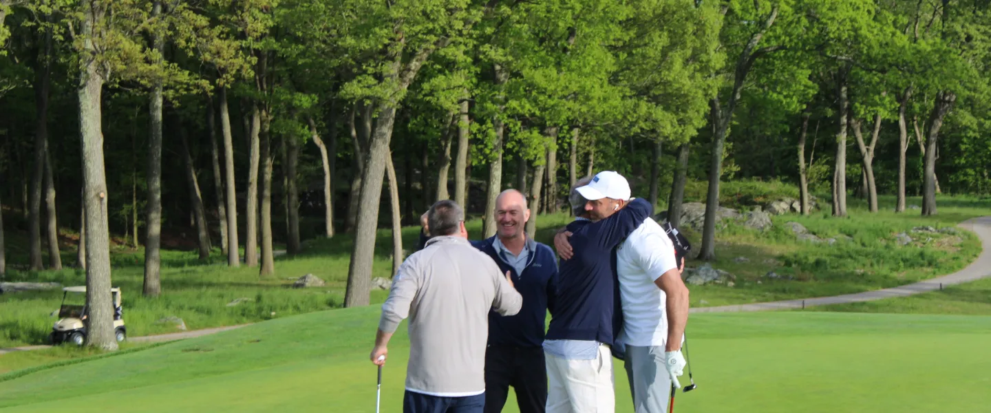 Golf foursome hugging on the green