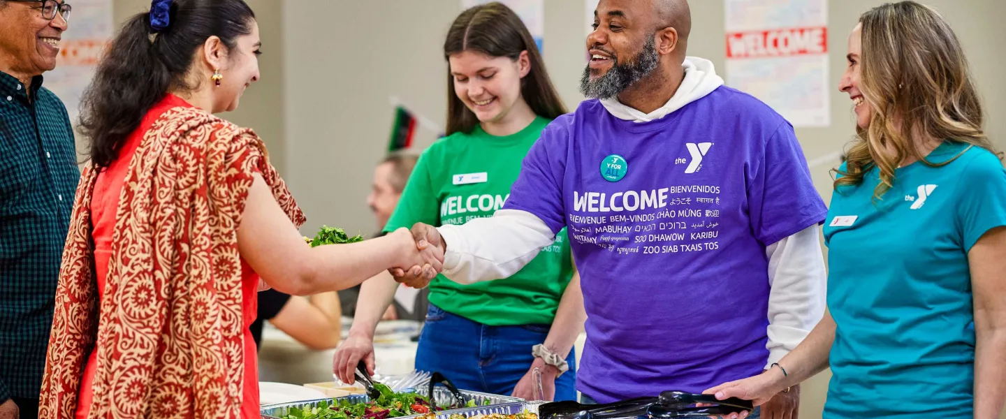 YMCA greeters welcome a man and woman with smiles and a handshake