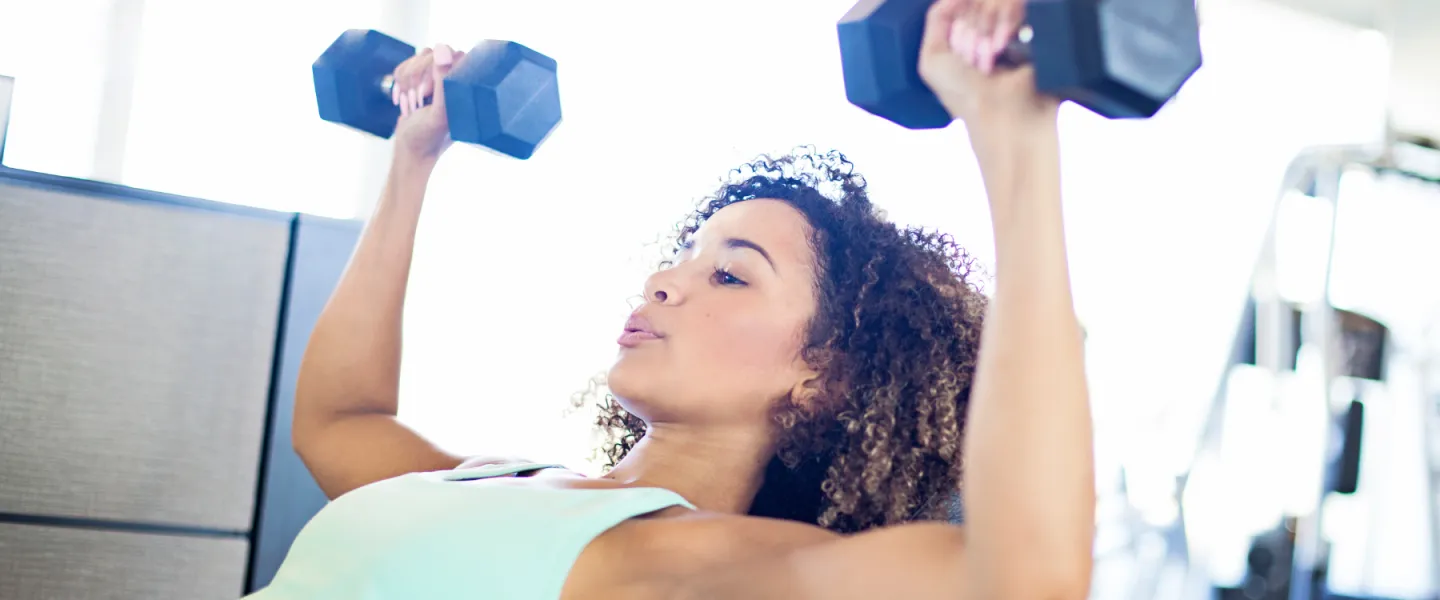 Woman doing chest press with free weights for the Women and Weights class