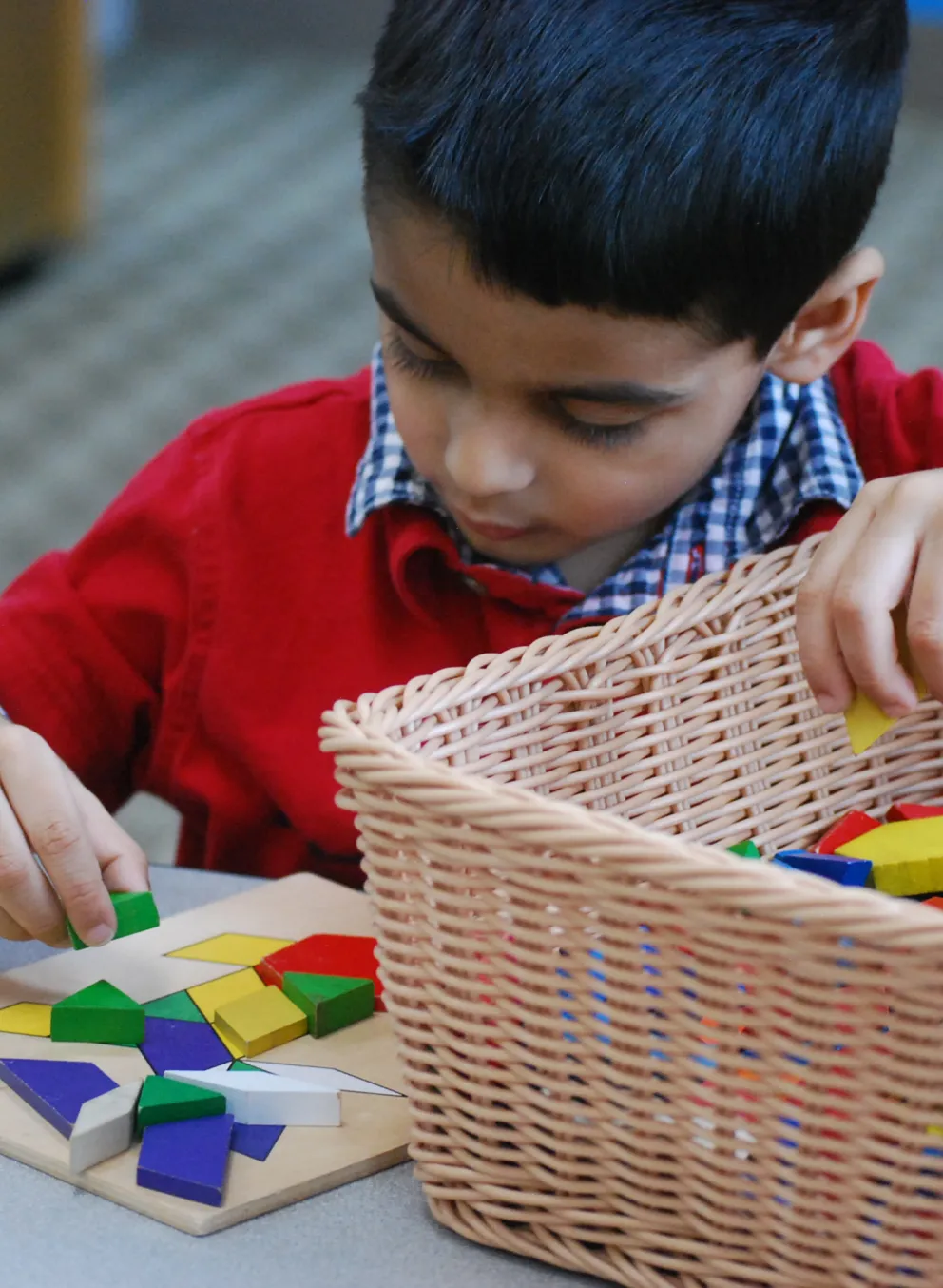 A preschool boy matches places colored blocks to match a pattern.