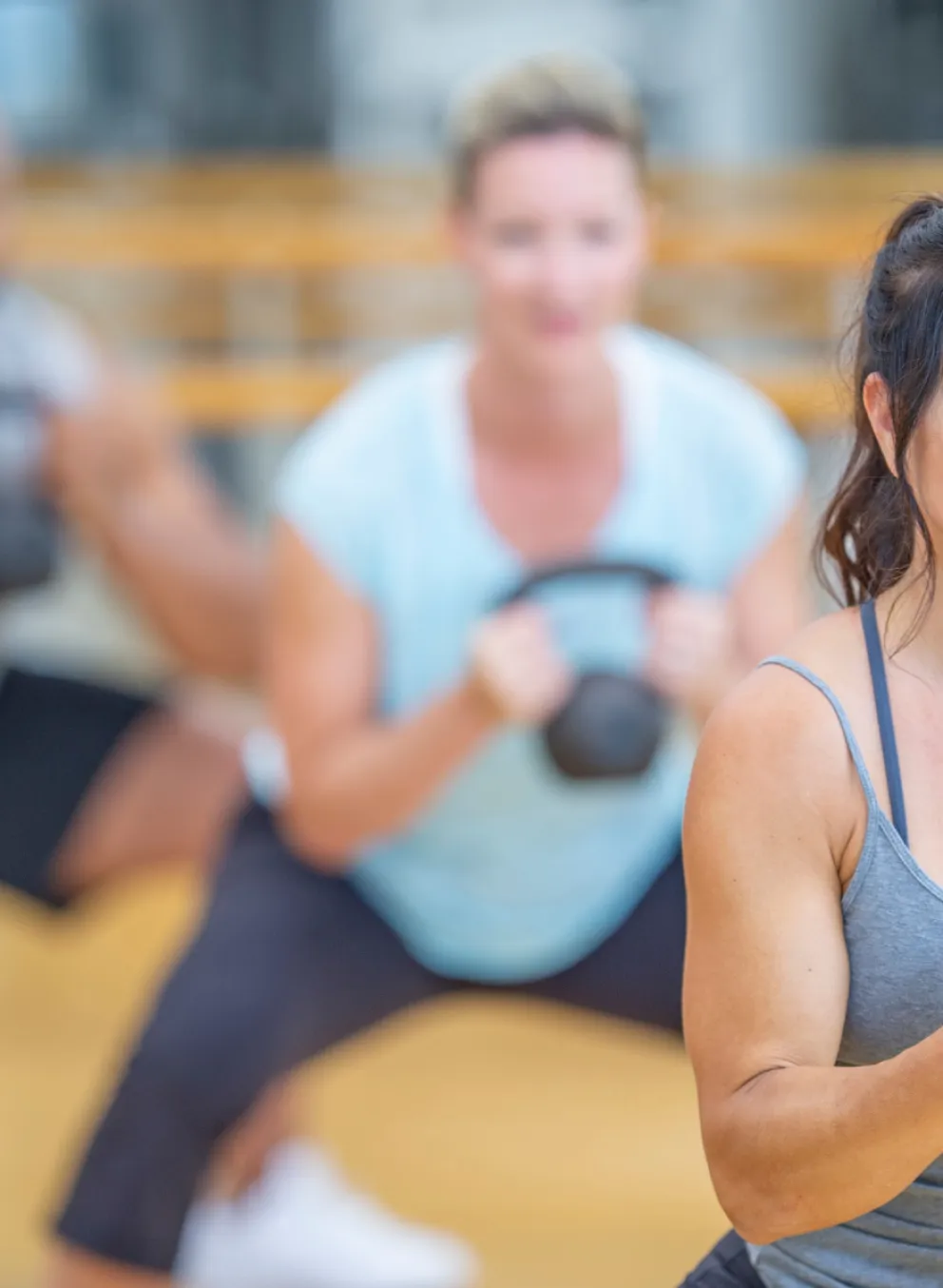 3 adults doing kettlebell squats in class