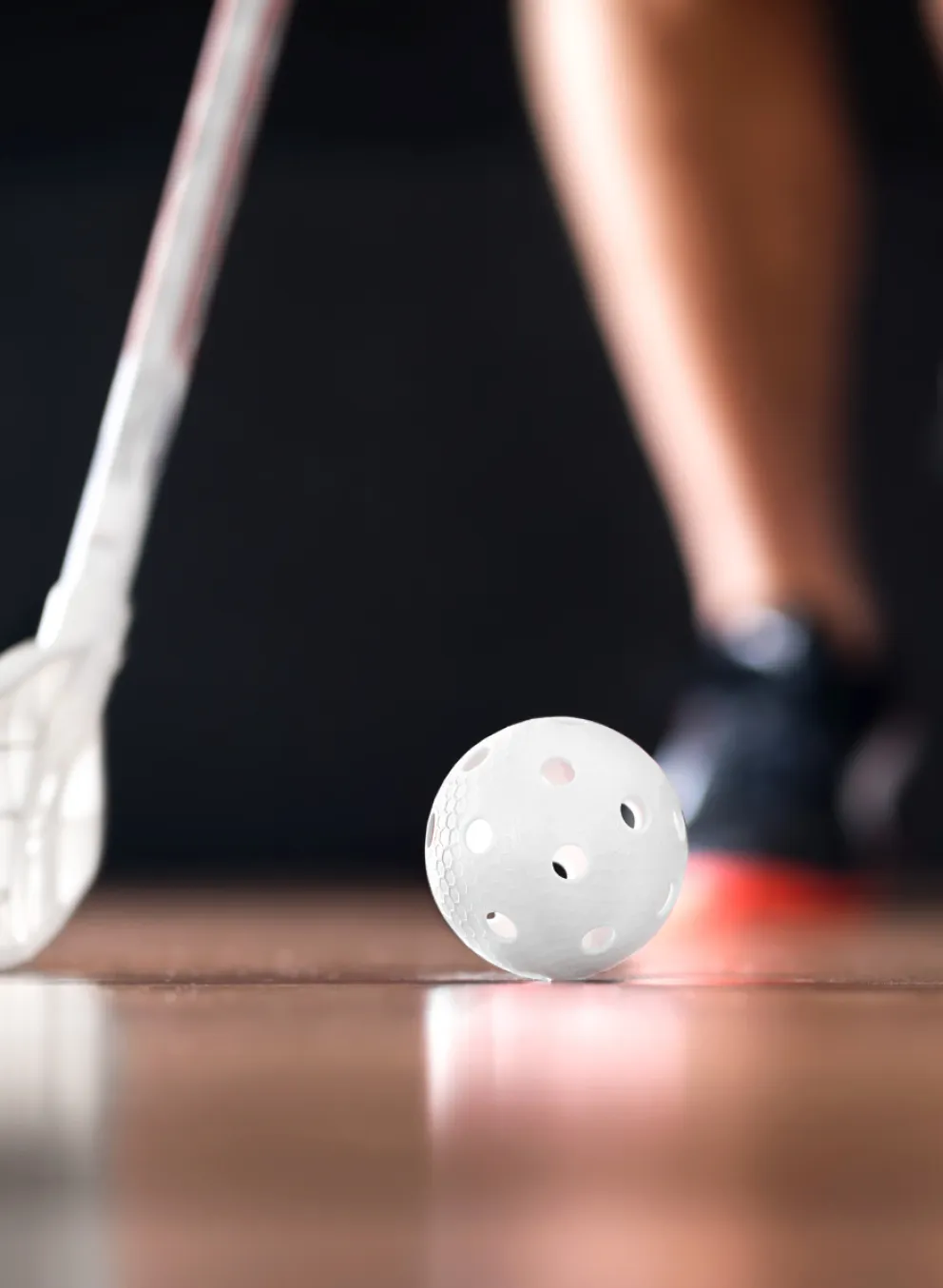 youth feet on court floor with ball and floor hockey stick