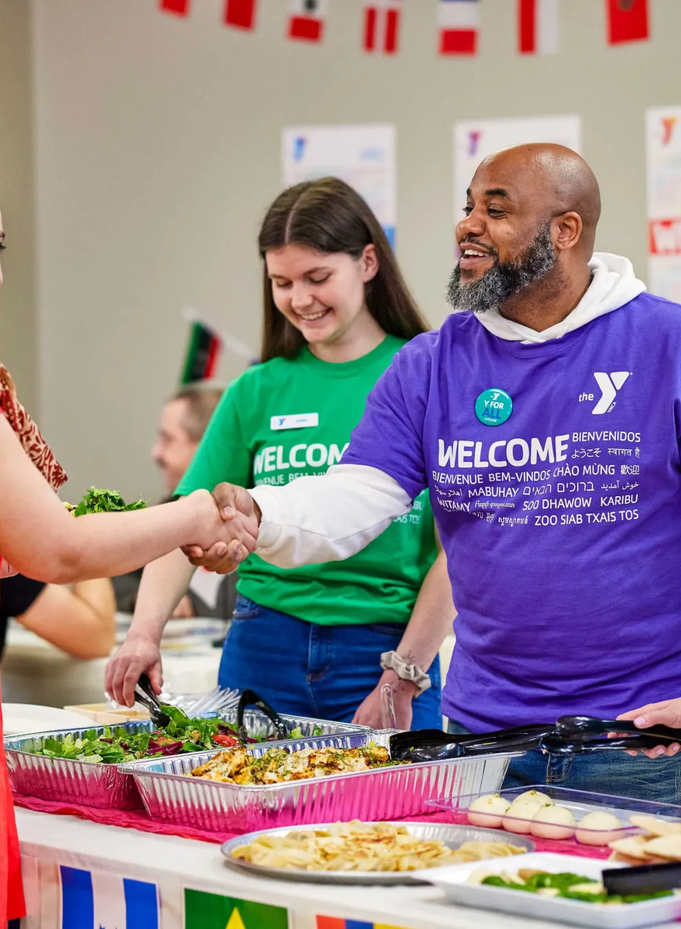 YMCA greeters welcome a man and woman with smiles and a handshake