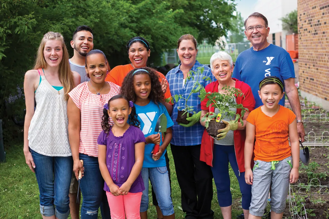 A photo of a group of people posing together in a garden with gardening tools