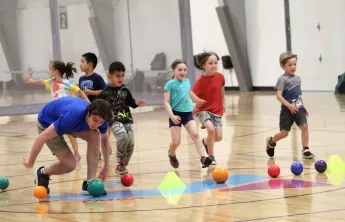 Campers at Camp Wells run for dodgeballs in the gym