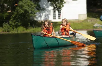 Two campers set off into the lake on their canoe.