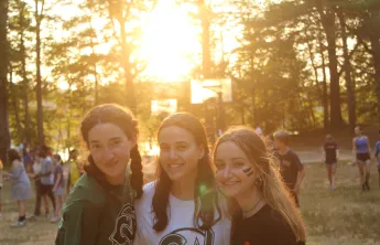 Three campers sand awaiting the closing ceremony as the sun begins to set. 