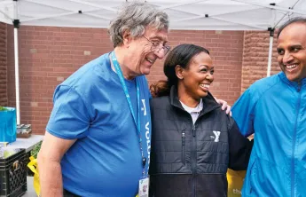 3 people smiling under a tent at the YMCA
