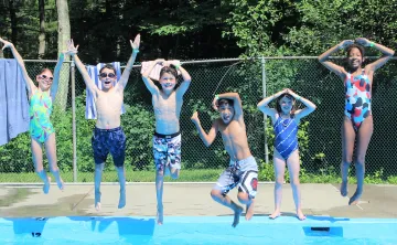 Campers jumping into the pool at Chickami