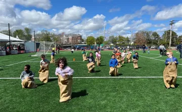 large group of children racing in potato sacs jumping toward the camera