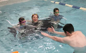 3 participants with swim instructor in the pool during class