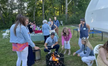 Party goers roast marshmallows over a fire at Camp Chickami