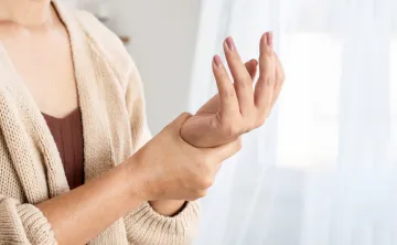 A person holding the base and wrist of their other hand