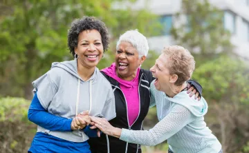 Three women laughing together and grasping hands