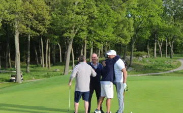 Golf foursome hugging on the green