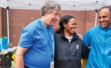 3 people smiling under a tent at the YMCA