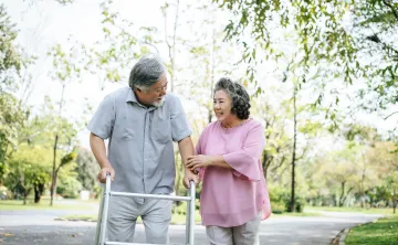 Older couple walking outside with walker