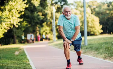 Older man stretching on a walk outside