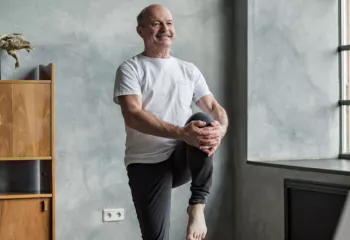 Senior man works performs a standing balance exercise