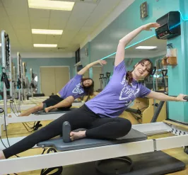 A young adult female and male on Pilates Reformer machines at the C.M. Gatton Beaumont YMCA.