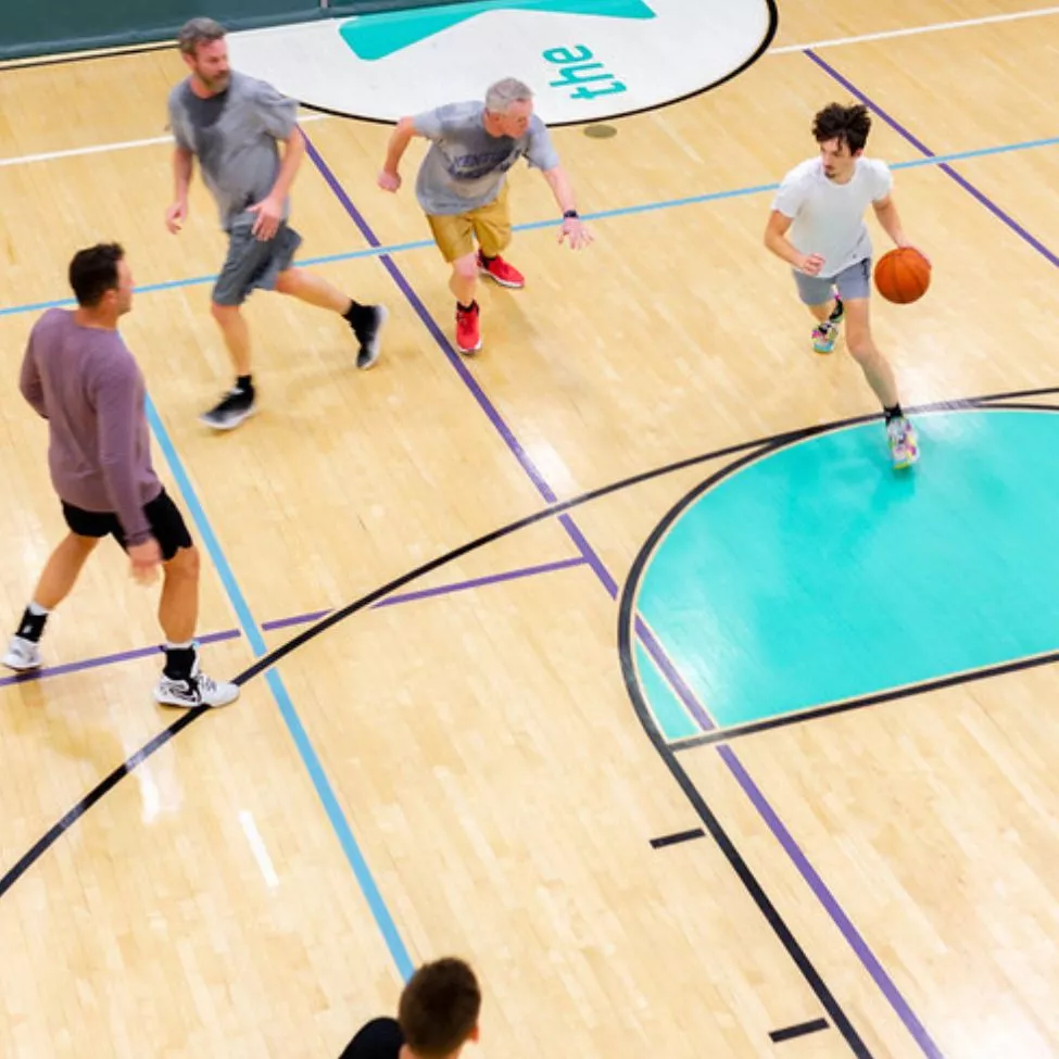 A group of young men play pick up basketball at the YMCA. 