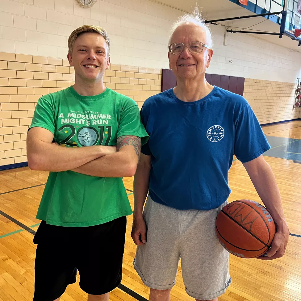 A young man and his grandfather pose in the gymnasium at the High Street YMCA.