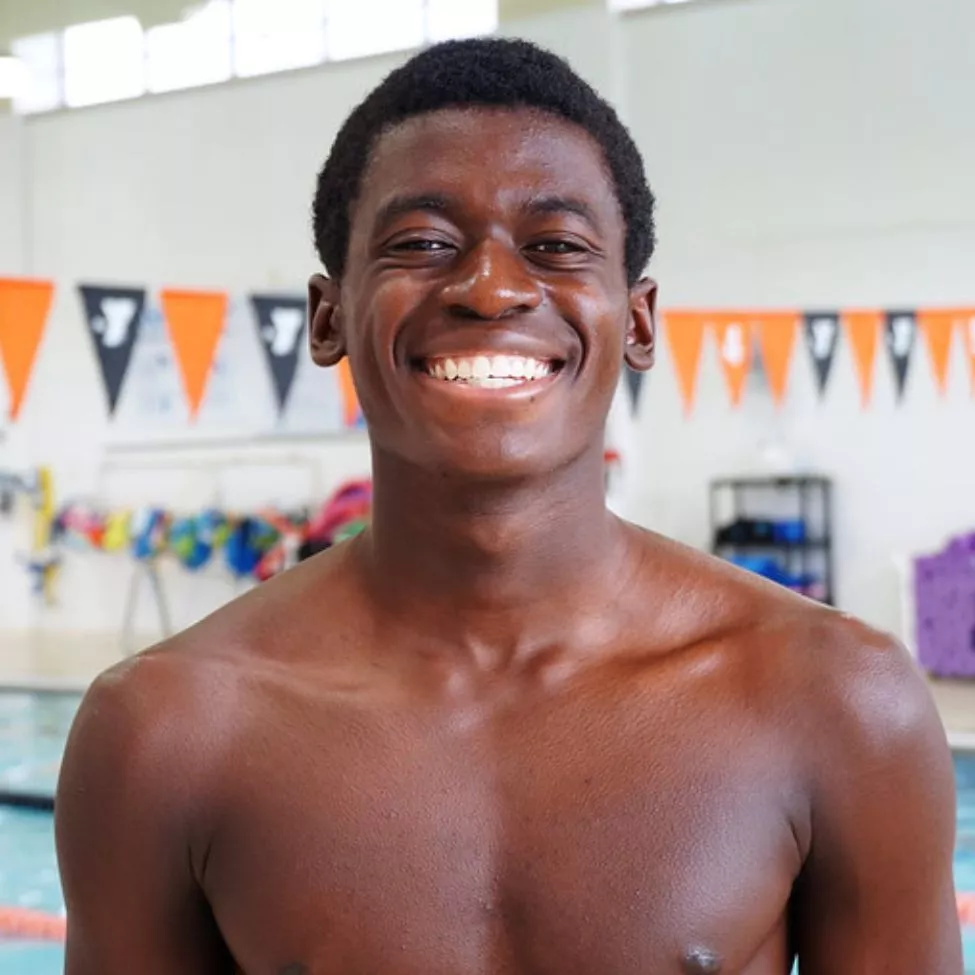 North Lexington YMCA Swimmer Philip L smiles for the camera by the indoor pool.