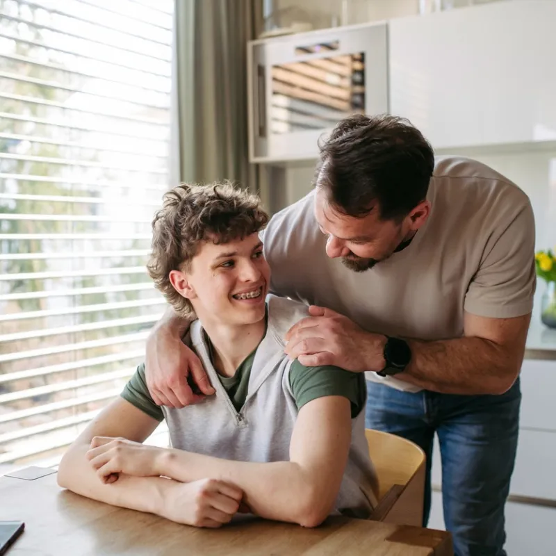 A parent smiles at their teenage child.