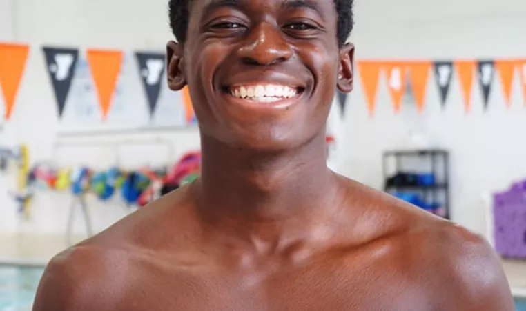 North Lexington YMCA Swimmer Philip L smiles for the camera by the indoor pool.