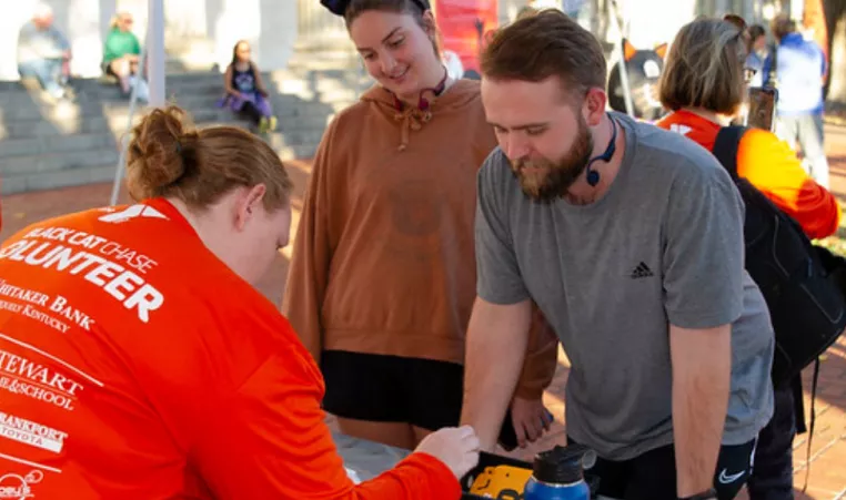 A YMCA of Central KY volunteer helps participants in the 2022 Black Cat 5K.