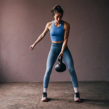 A person holds a kettlebell during a cardio and strength workout.