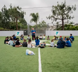 Kids sitting in a circle as camp counselor speaks