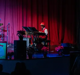 Child playing piano on stage during a holiday performance