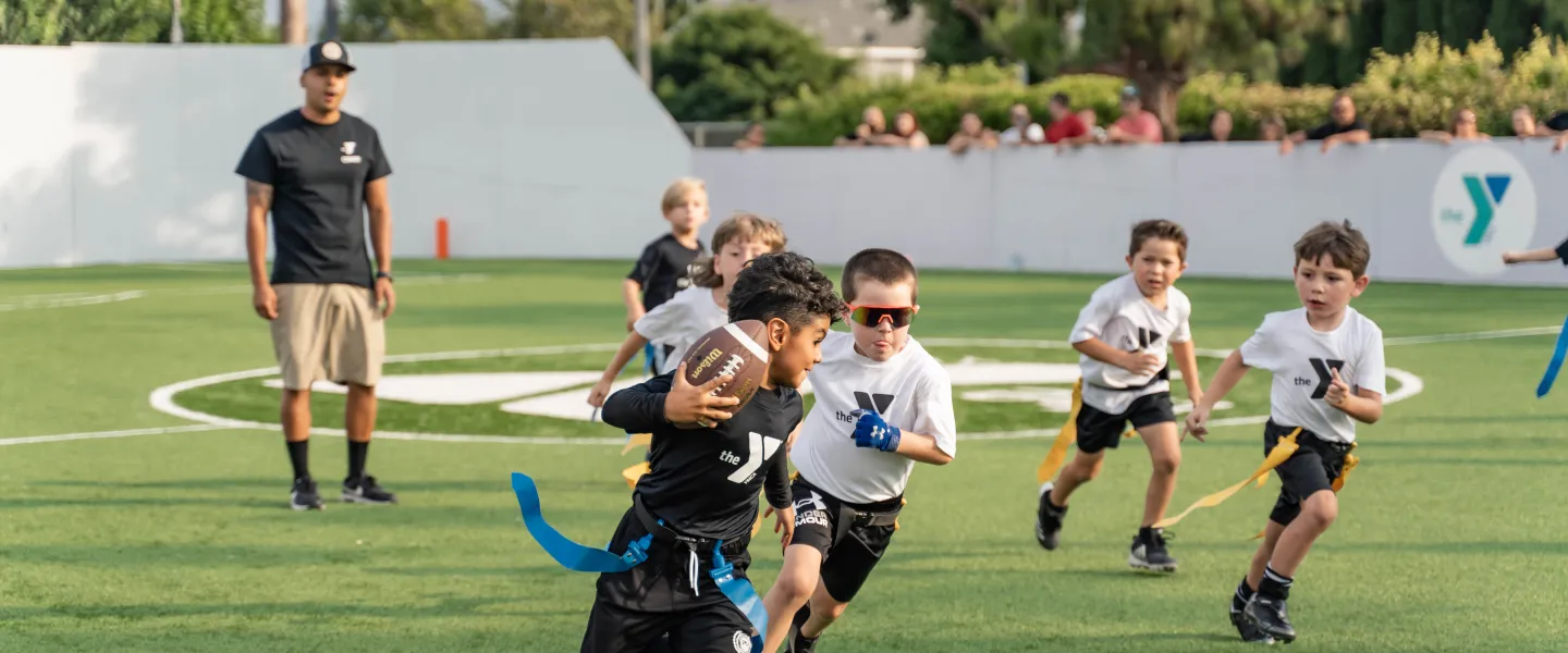 Young athlete running with a football during a flag football game
