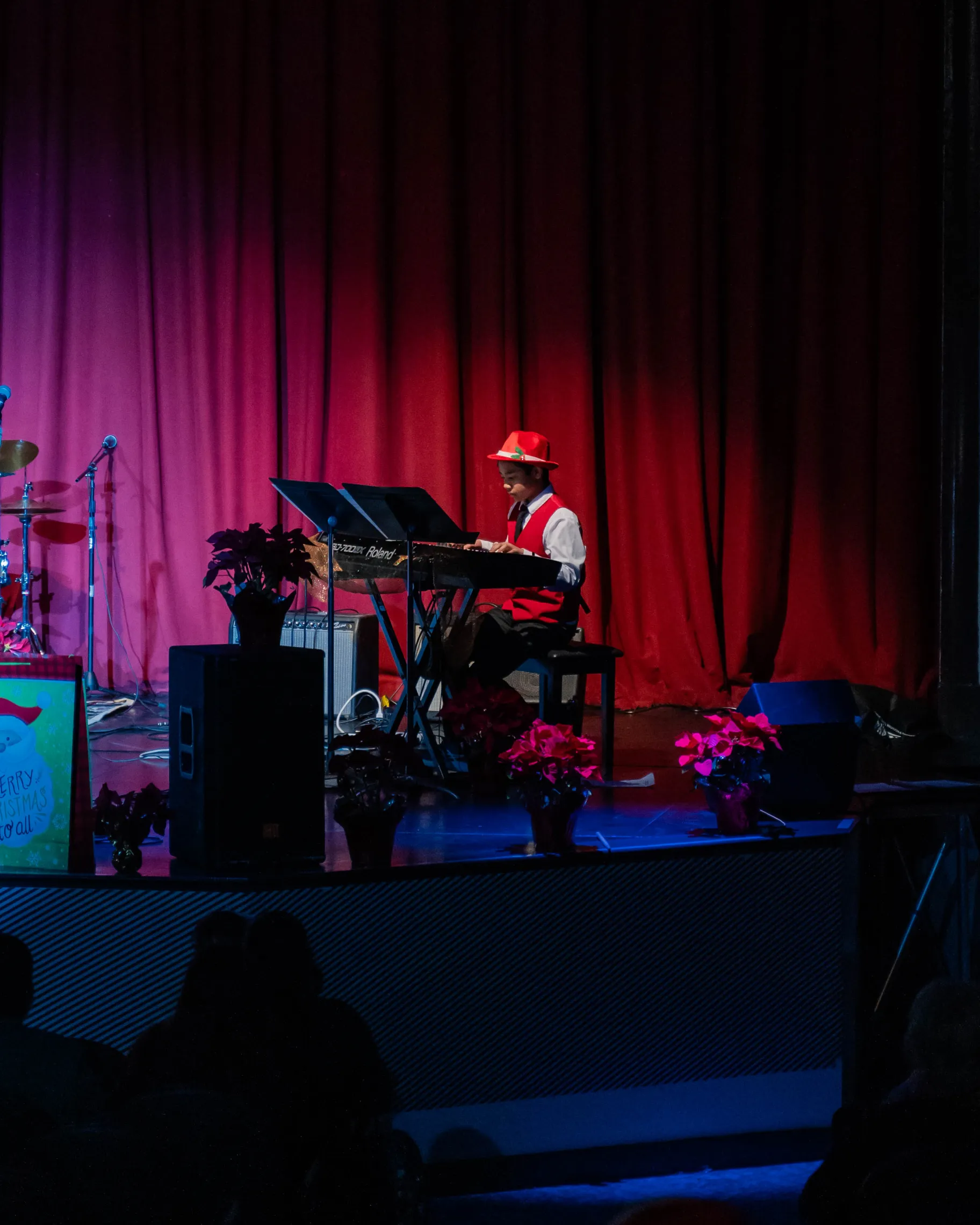 Child playing piano on stage during a holiday performance