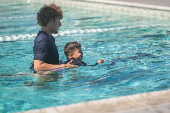child swimming with swim instructor